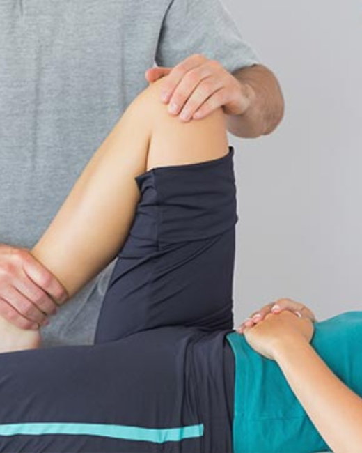 A woman is having her knee examined by a physical therapist.