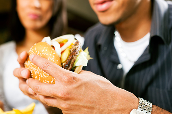 A man and a woman eating a hamburger.
