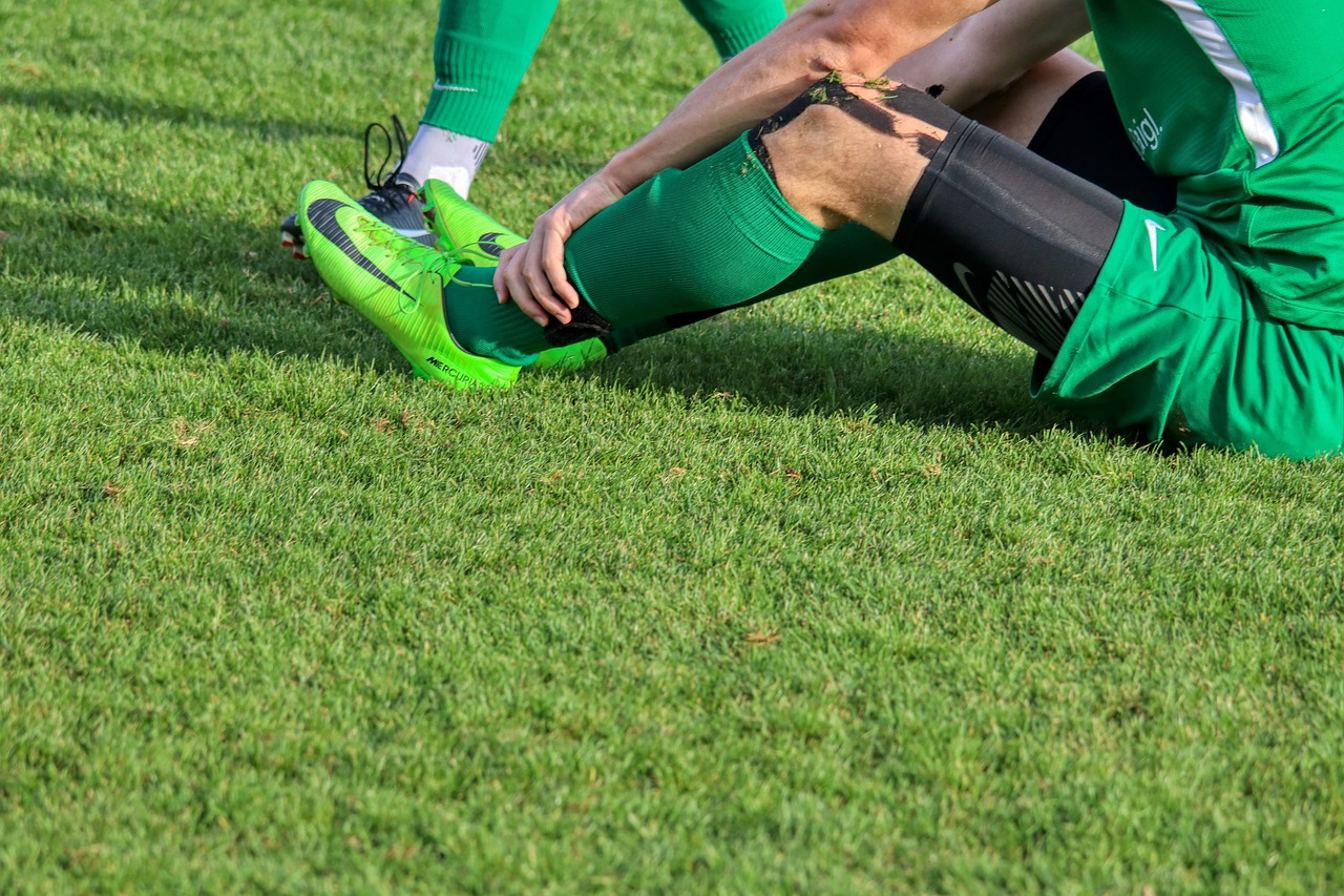 A soccer player is sitting on the ground.