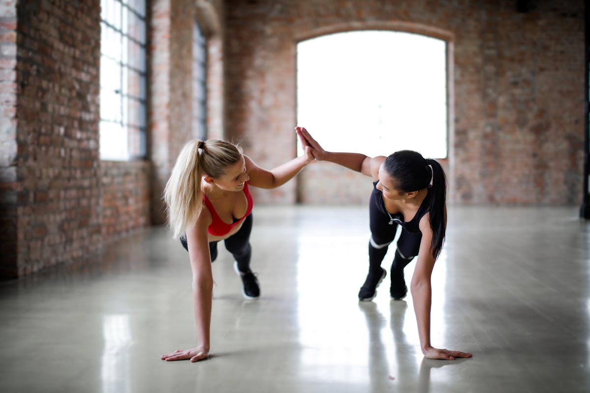 Two women doing push ups in a gym.